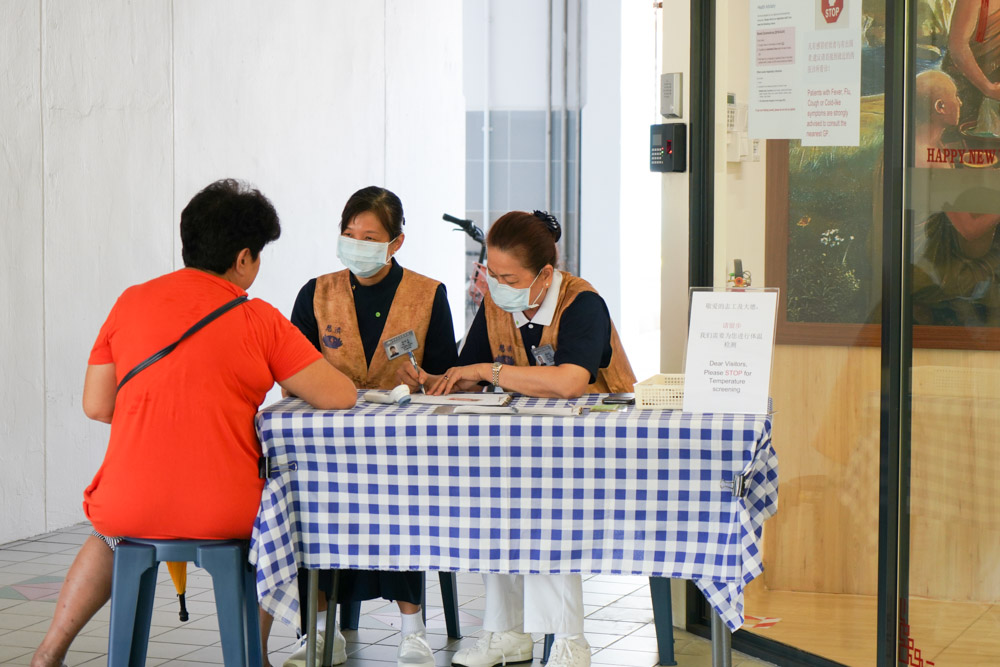 志工在中医义诊中心（卡迪）为看诊患者测量体温、询问旅游史，严防新冠病毒传播。摄 / 曾美珍